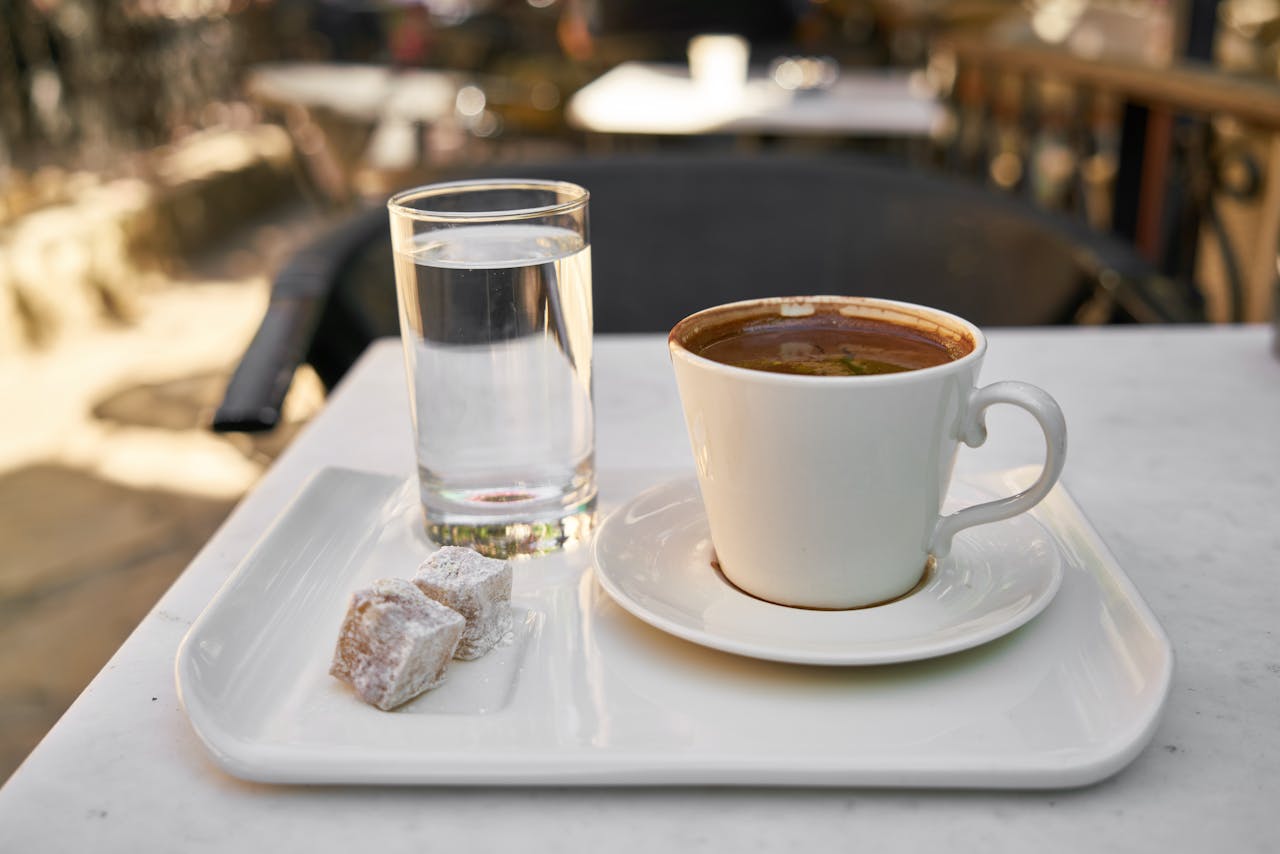 A cup of Turkish coffee with Turkish delight and water on a tray in a Turkish café setting.