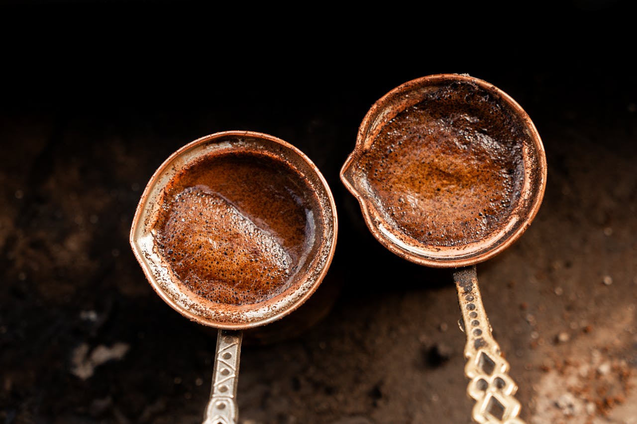 creative-02 Close-up of two copper pots brewing strong Turkish coffee over hot sand.